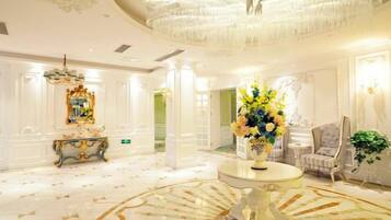 Eine luxuriöse Lobby mit einem prächtigen Kronleuchter, einem runden Marmortisch und einer Blumenkomposition.