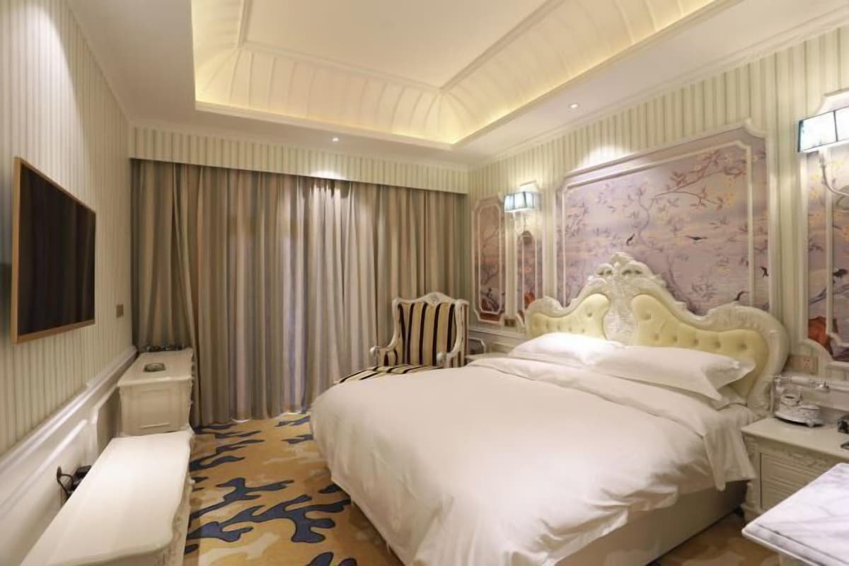 Une chambre d’hôtel avec un grand lit, une table de chevet, une chaise, un bureau et un grand miroir.