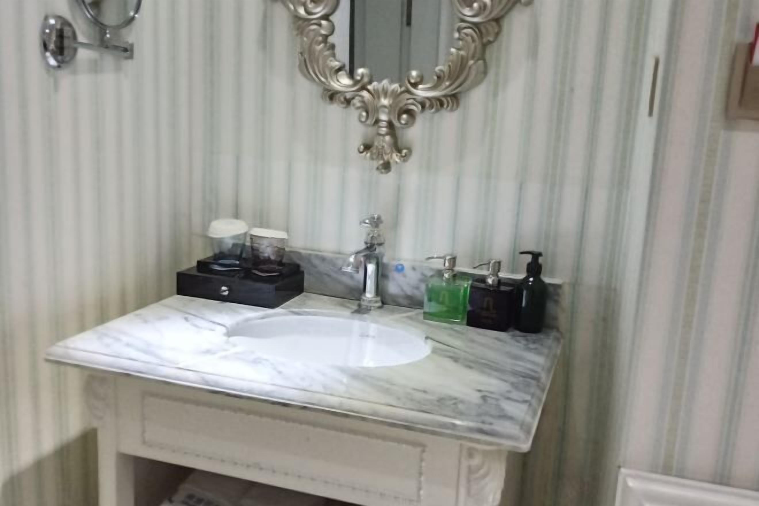 A bathroom with a marble sink, a mirror, and toiletries.