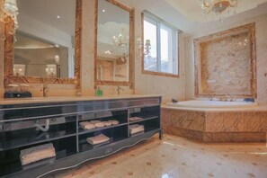 Une salle de bain luxueuse dotée d’un grand meuble-lavabo, de plusieurs miroirs, d’un lavabo en marbre et d’un porte-serviettes intégré.
