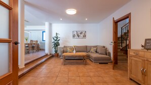 Ein Wohnzimmer mit einer Couch, einem Couchtisch und einem Topfpflanzen. Eine Treppe führt zu einer anderen Ebene.
