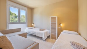 Een slaapkamer met een bed, een bank, een kledingkast en een raam met uitzicht op bomen.