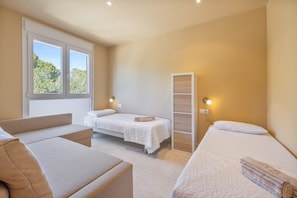 Une chambre à coucher avec un lit, un canapé, une armoire et une fenêtre donnant sur des arbres.