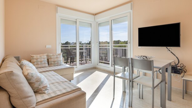 Een moderne woonkamer met een bank, eettafel, stoelen en een televisie.