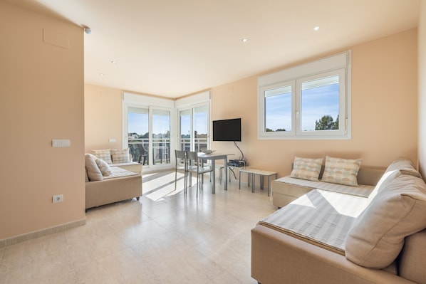 A spacious living area with a sofa, a dining table, and a TV.