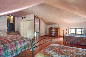 A bedroom with two beds, a dresser, and a window.