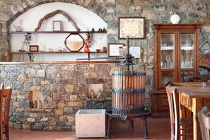 A stone wall, wooden barrels, a metal stand, a cabinet with glass doors, and a tiled floor.