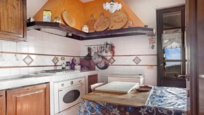 Een keuken met een kookplaat, oven en hangende keukengerei.