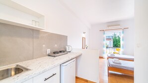 Cozinha compacta com pia, cafeteira e lava-louças. Há uma cama com vista para o exterior.