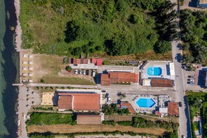 An aerial view of a coastal property with multiple buildings, a swimming pool, and a beach area. - Saint Peter Bay - Basic Room: Vacation Apartment with Shared Pool & Wi-Fi (Corfu)