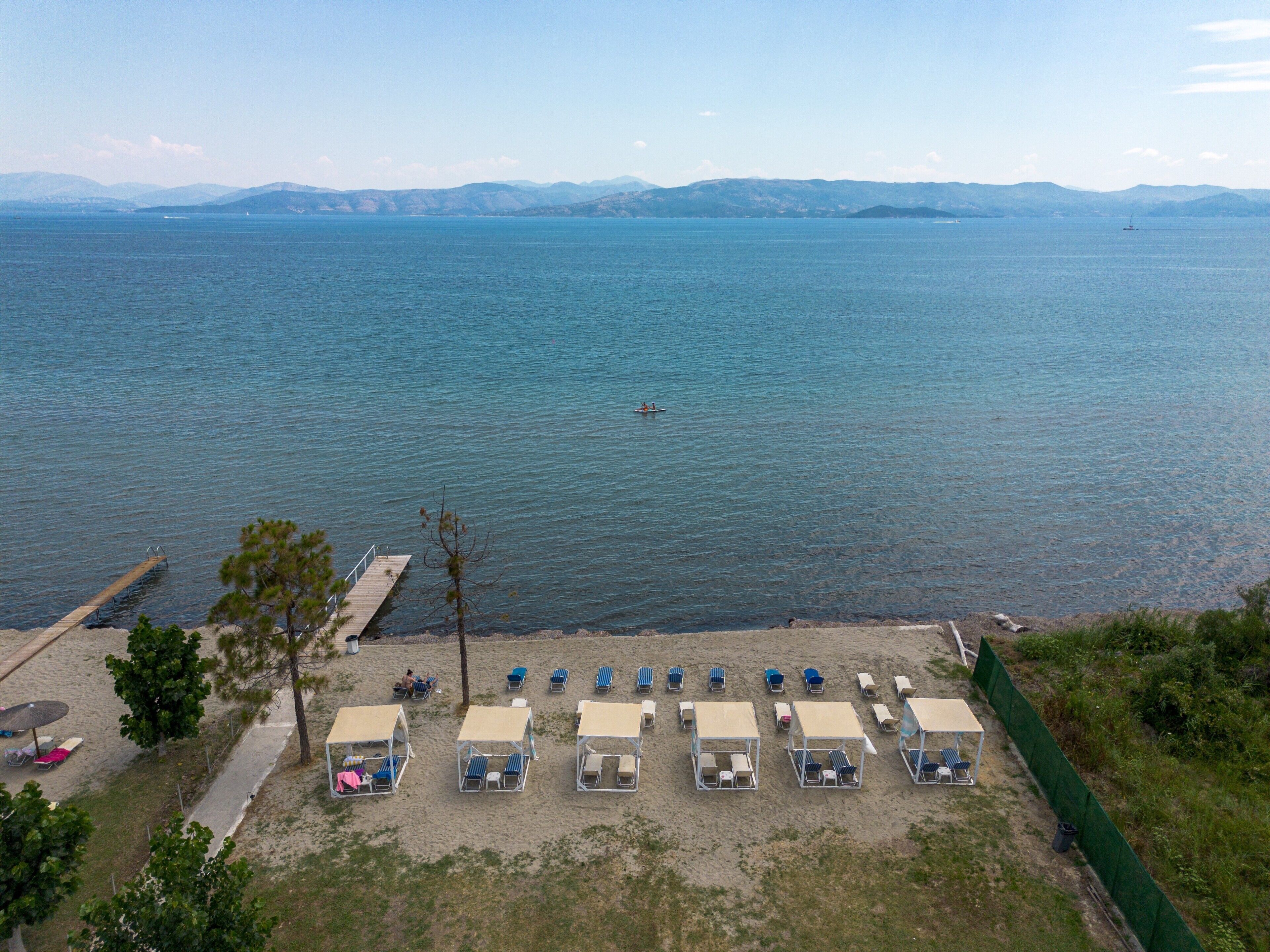 Une plage bordée de rangées de transats et d’une jetée qui s’avance dans l’eau.