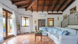 A living room with a wooden ceiling, a sofa, a coffee table, and a staircase.