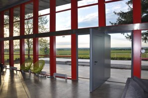 A modern interior with large windows, a door, and a view of a green landscape. - Villa 'Maison Le Corbusier' with Mountain View, Private Terrace and Wi-Fi (Doncourt-lès-Conflans)