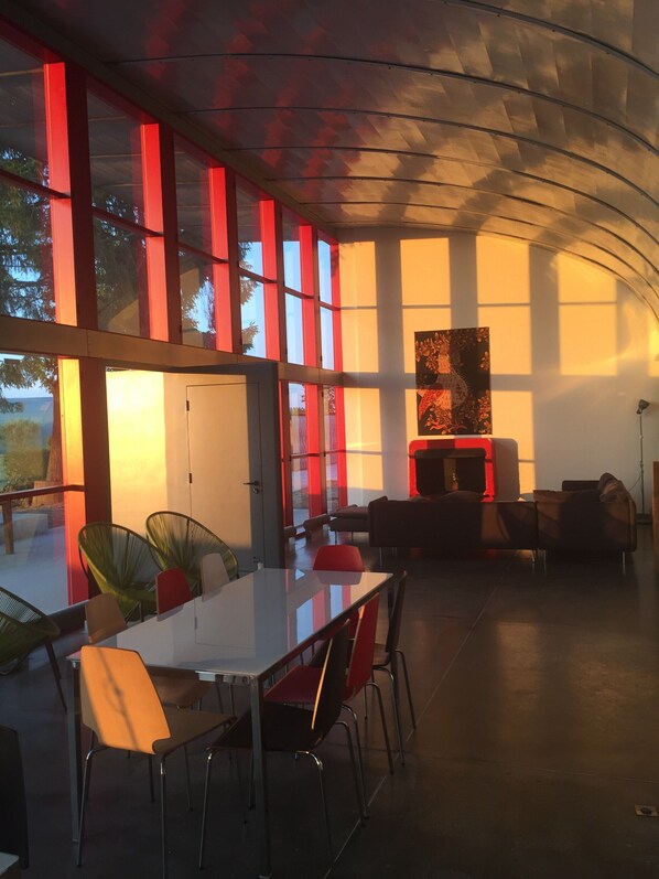 Un intérieur moderne avec un mur de verre, des touches de rouge et une cheminée.