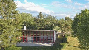 Un edificio moderno con fachada de vidrio, rodeado de árboles y césped.