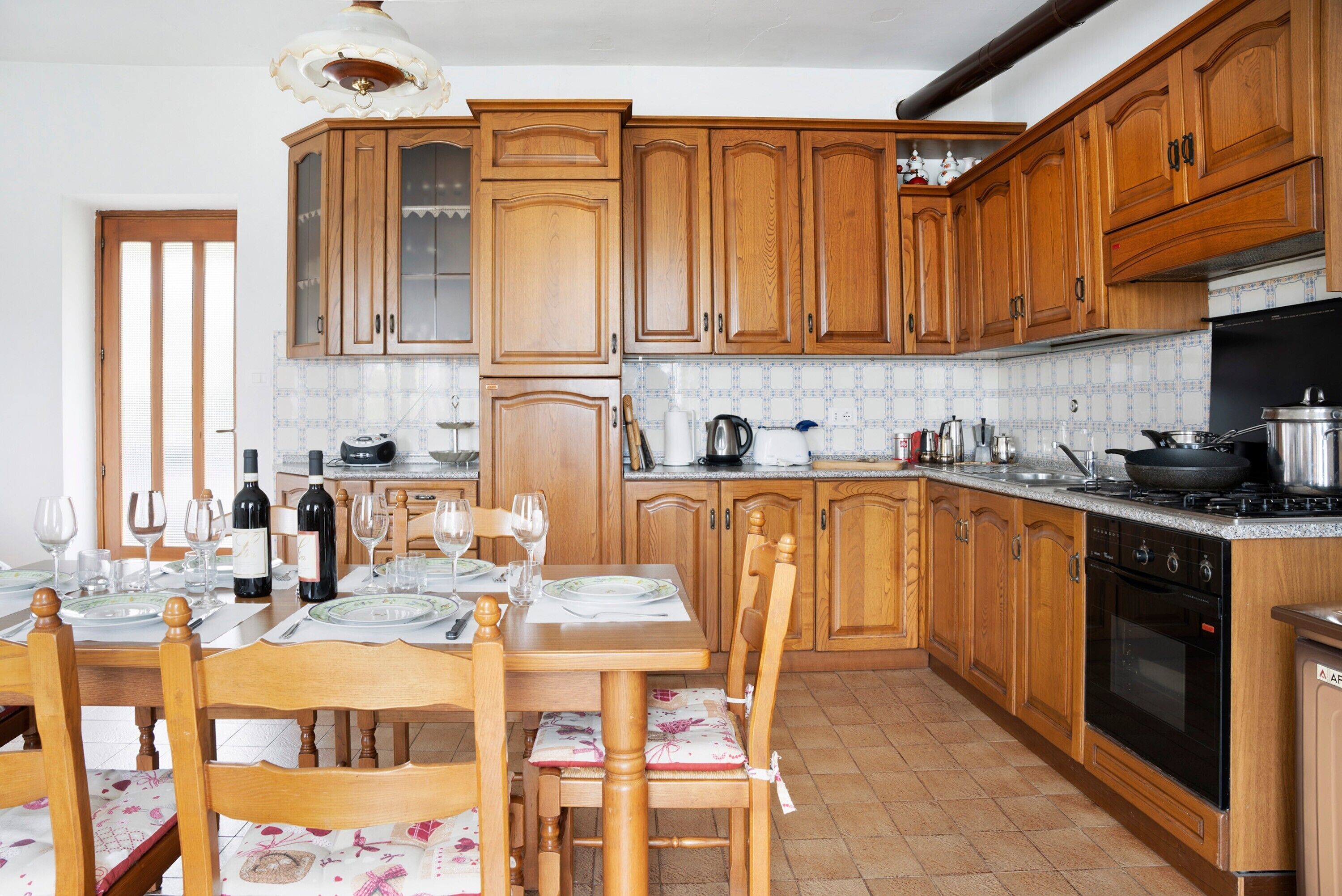 A kitchen with wooden cabinets, a dining table set for four, and a stove.