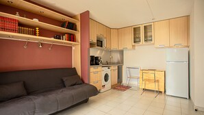 Un espacio habitable compacto con sofá, lavadora, microondas y refrigerador.