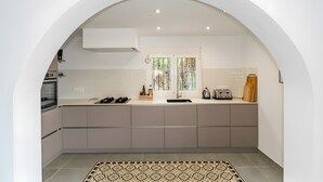 A modern kitchen with a built-in oven, a sink, and a window with decorative glass. - Villa "Casa Silencio" with Sea View, Private Pool & Wi-Fi (Cómpeta)
