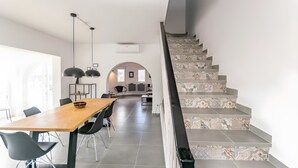 A modern interior with a wooden dining table, black chairs, a staircase with patterned tiles, and a kitchen in the background. - Villa "Casa Silencio" with Sea View, Private Pool & Wi-Fi (Cómpeta)