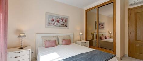 Ein Schlafzimmer mit Bett, Nachttischen, einem Spiegel und einem Kleiderschrank.