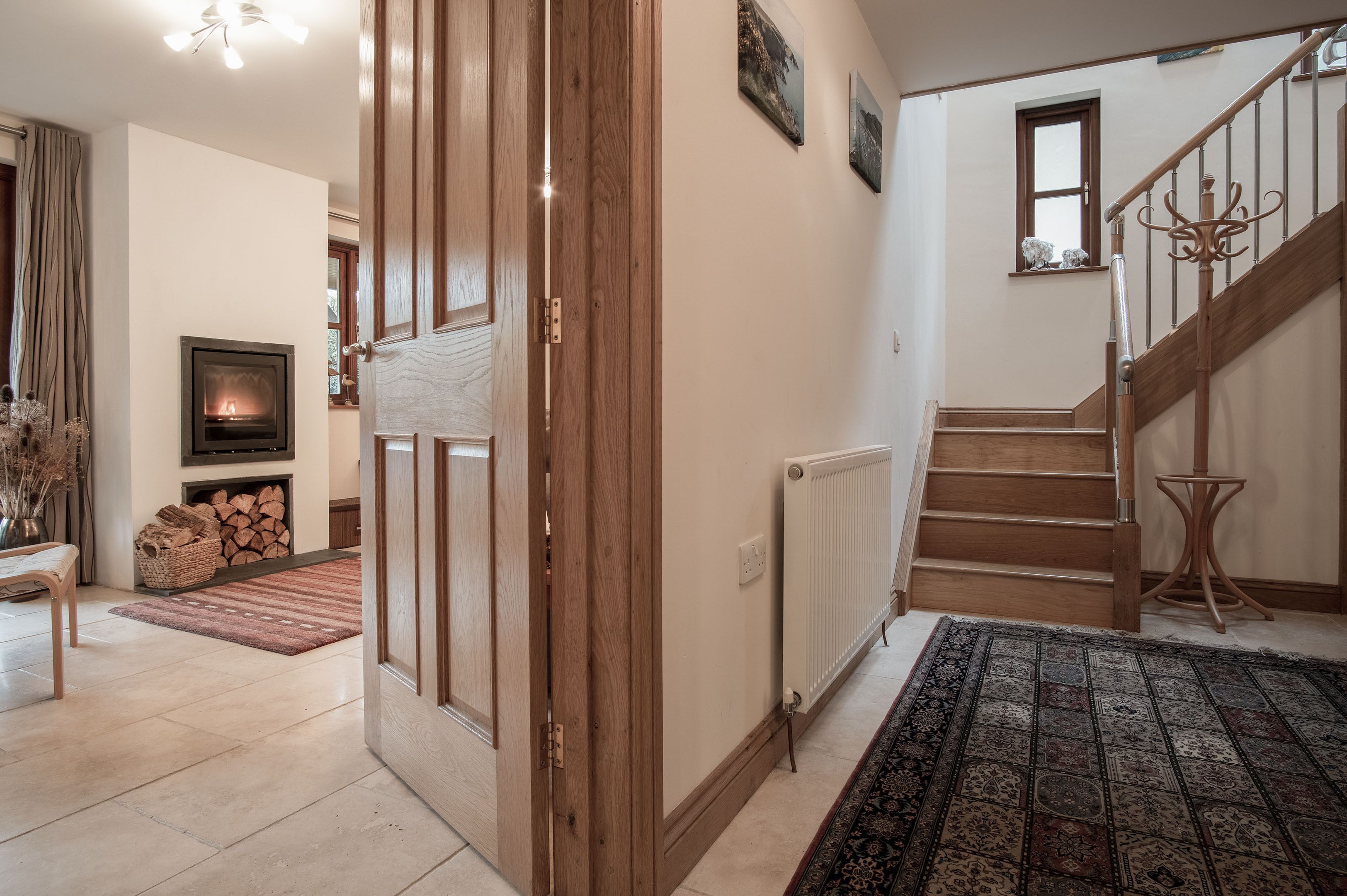 A living room with a fireplace, a staircase, and a view of the outside.