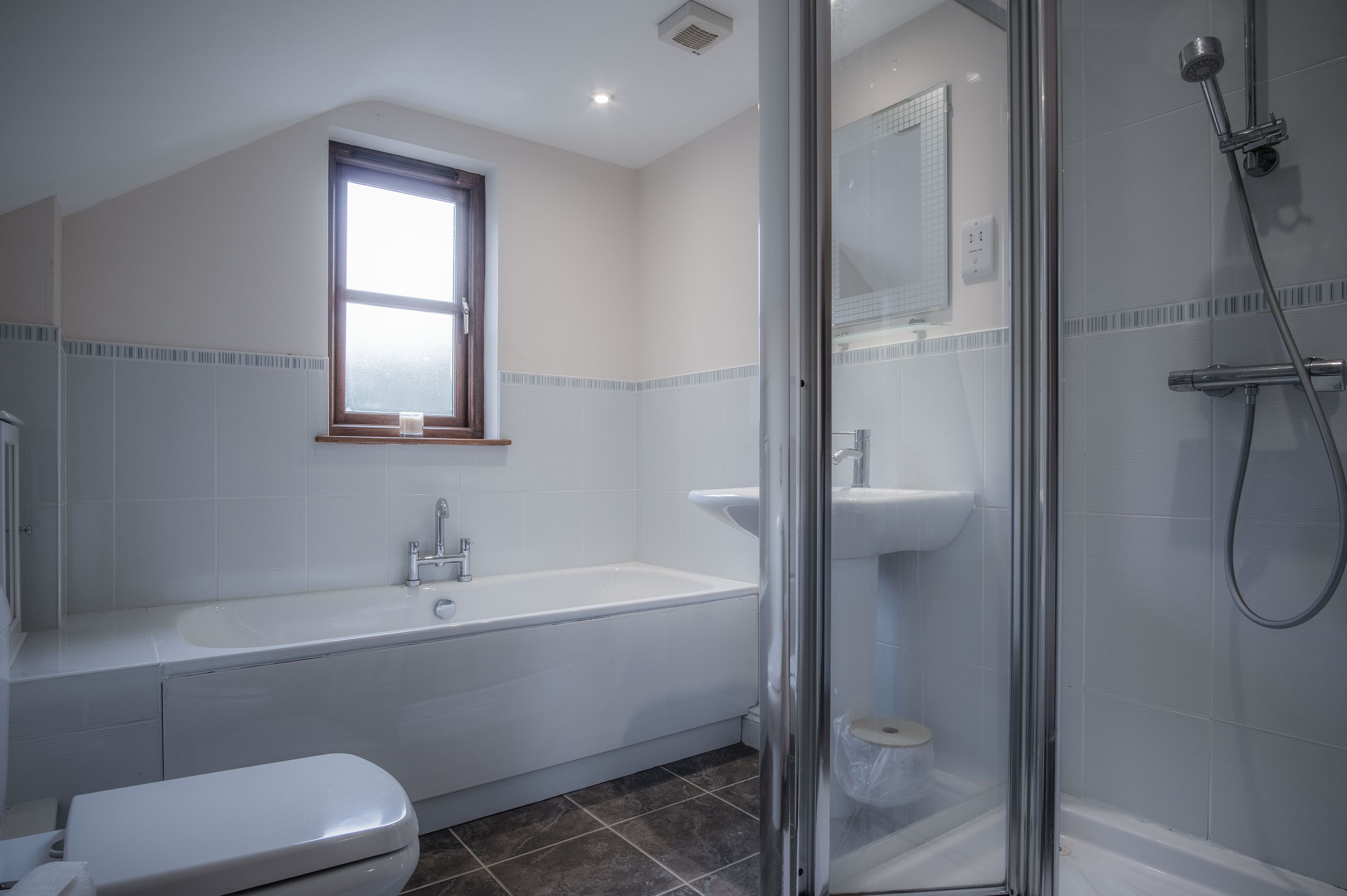 A modern bathroom with a bathtub, toilet, and shower area.