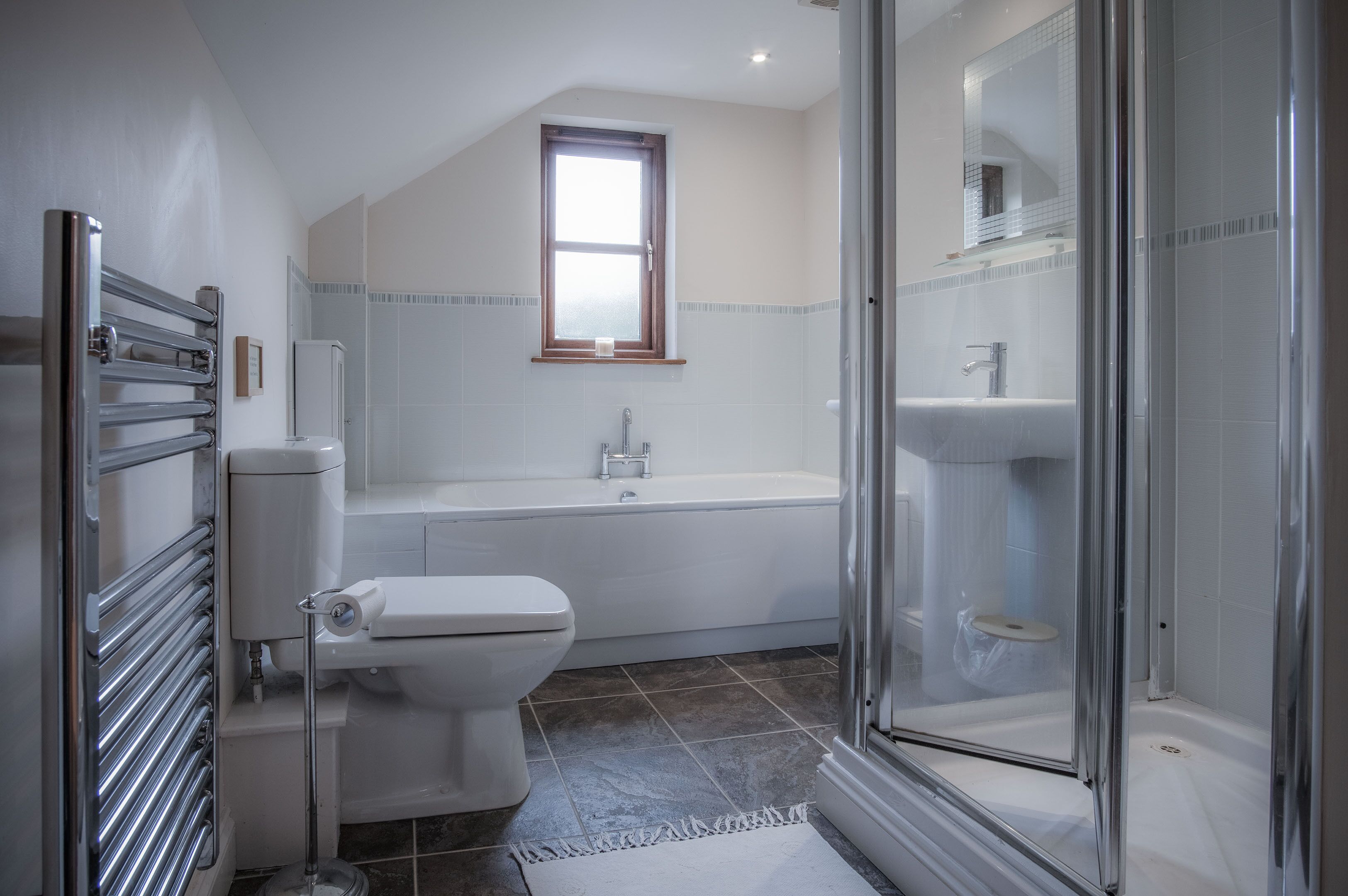 A modern bathroom with a toilet, bathtub, and shower.