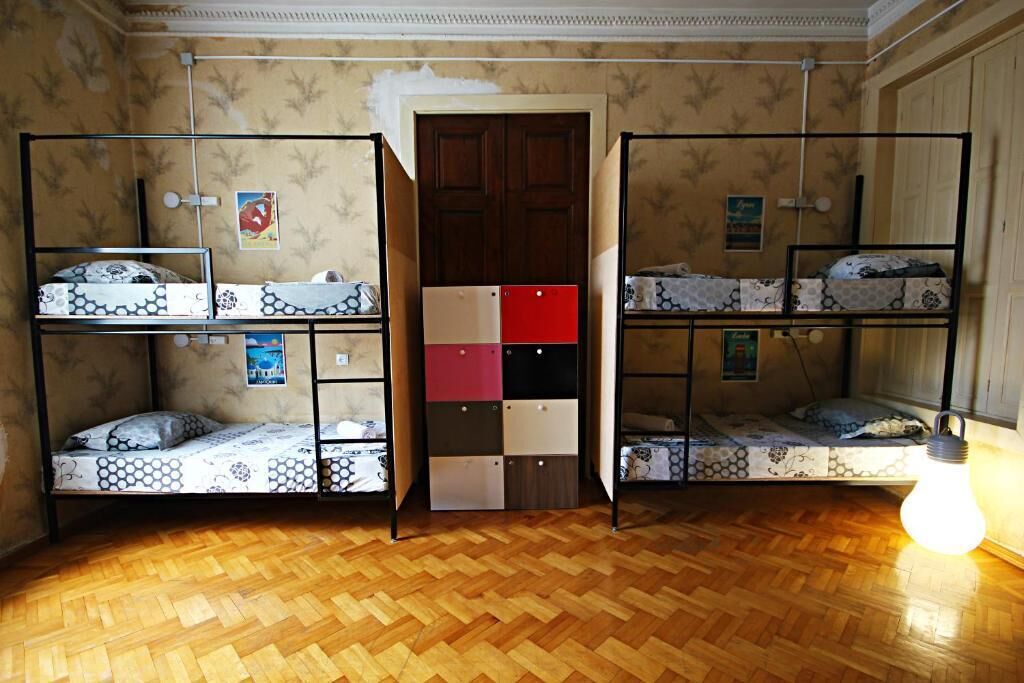 Una habitación con literas, suelo de madera y una puerta con un panel rojo.