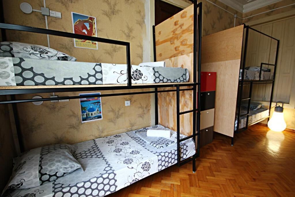 A dormitory room with bunk beds, a wooden floor, and a poster on the wall.