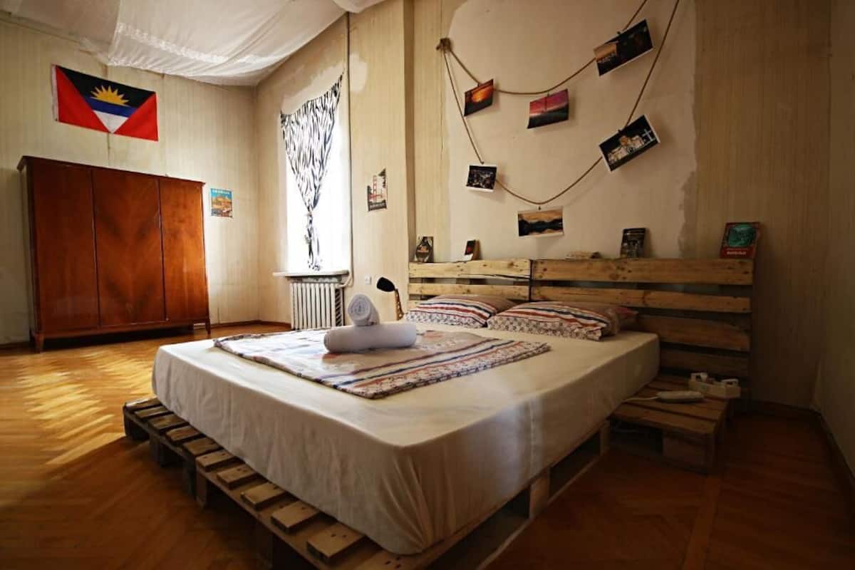 Un dormitorio con cama, armario de madera e una bandera en la pared.