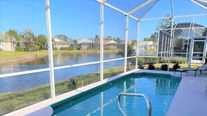An indoor swimming pool with a view of a lake and houses in the background. - Paradise Bound - Great Prices, Heated Pool, 5 Min to Beaches (Bradenton)