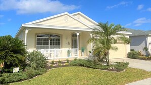 A single-story house with a front porch, a garage, and a well-maintained lawn with various plants. - Paradise Bound - Great Prices, Heated Pool, 5 Min to Beaches (Bradenton)