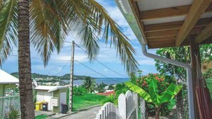 A residential area with a view of the sea, houses, and a palm tree. - Bélya - Peaceful gîte with terrace and sea view (Le Vauclin)