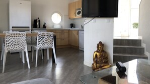 Une cuisine moderne avec un coin repas, un téléviseur fixé au mur et une statue de Bouddha.