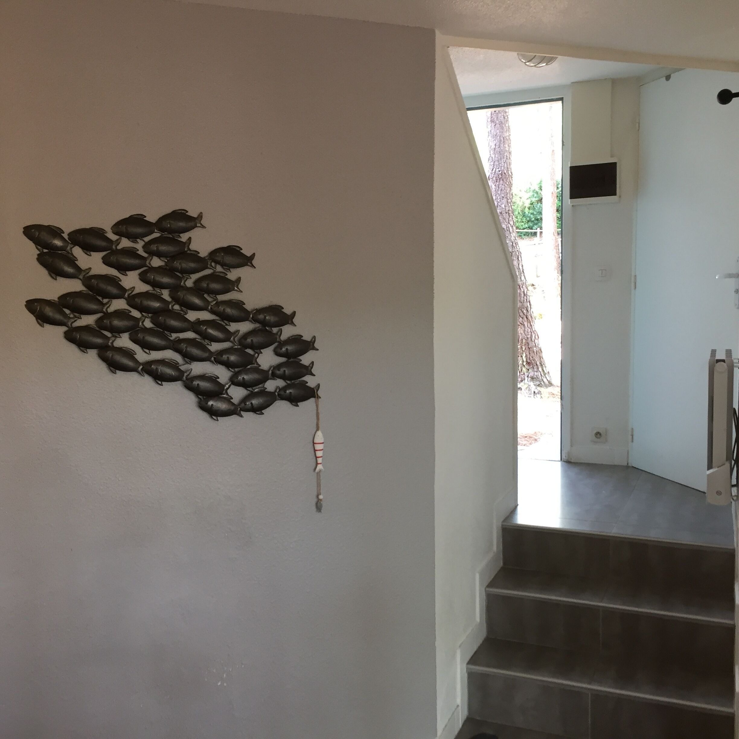 A staircase with a wall-mounted decorative fish sculpture.
