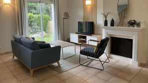 A living room with a sofa, a chair, a TV, and a fireplace. - House near beaches, classified 3*- quiet (Névez)