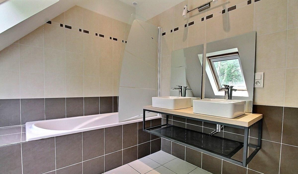 Un bagno moderno con una vasca freestanding, due lavabi e un grande specchio.