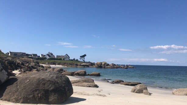A coastal landscape with large rocks, a sandy beach, and a row of houses with a prominent tree on a hill. - House near beaches, classified 3*- quiet (Névez)