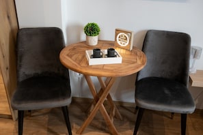 Relax in a cozy seating area with a round table, potted plant, and a warm, inviting atmosphere.