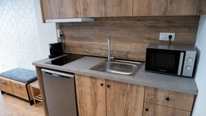 A modern kitchen with wooden cabinets, a stainless steel sink, a microwave, and a dishwasher. - Cozy modern studio in Thessaloniki (Thessaloniki)