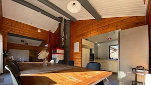 Zona pranzo in legno con un tavolo grande, sedie e una cucina sullo sfondo.
