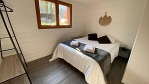 Una camera da letto con un letto, una finestra, un elemento decorativo a parete e un pavimento in legno.