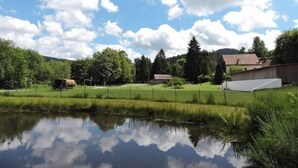 A rural landscape with a pond, a wooden cart, and a house with a red roof. - Ferme des Jonquilles à Gérardmer (15p) (Gérardmer)