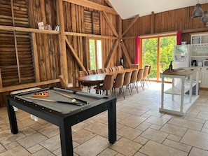Interior em madeira com mesa de bilhar, sala de jantar e cozinha.