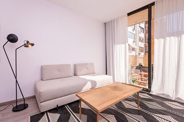 A modern living room with a sofa, a wooden coffee table, and a floor lamp.