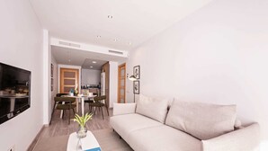 Un salon moderne avec un canapé, une table basse ornée d’un vase, et un coin repas comprenant des chaises et une table.