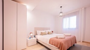 Um quarto moderno com uma cama grande, mesas de cabeceira e uma janela com cortinas.