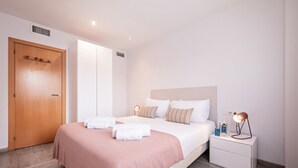 Moderni hotellihuone, jossa on suuri sänky, yöpöydät ja puinen ovi.