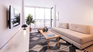 Een moderne woonkamer met een bank, een salontafel, een televisie en een plant.