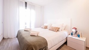 Een slaapkamer met een bed, nachtkastje, lamp en raam met gordijnen.